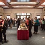An image of the reception, including the buffet tables in the middle of the room and many people clustered throughout